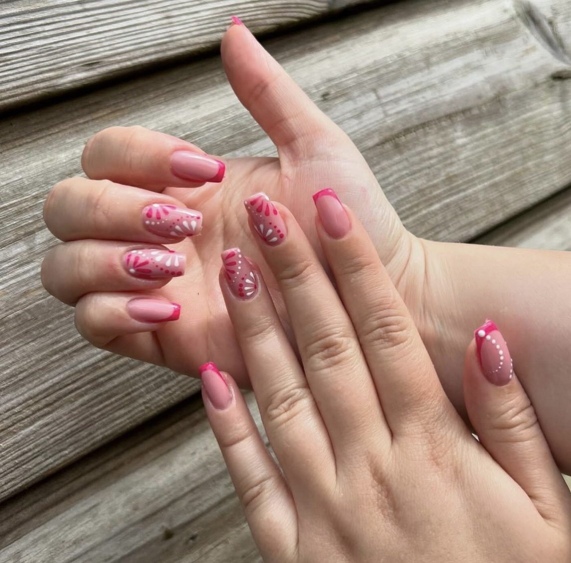 Roze nagels met French tips en nail art op een houten achtergrond