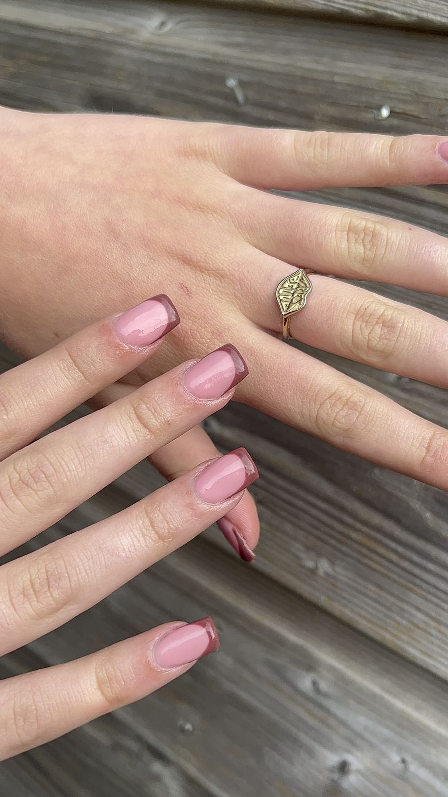 Bruine French tips op een hand tegen een houten achtergrond