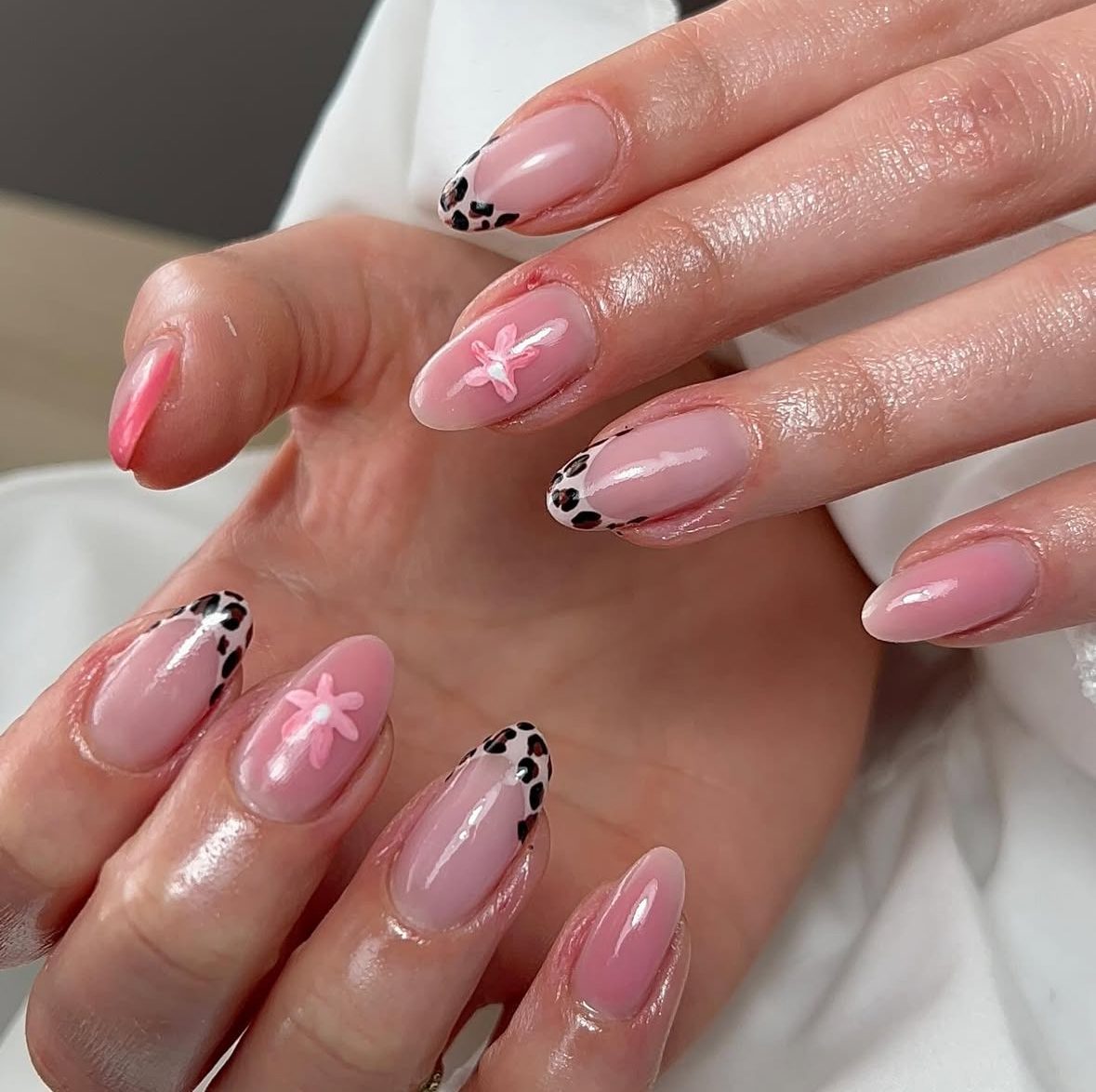 Amandelvormige roze nagels met koeienprint tips en een bloemetje
